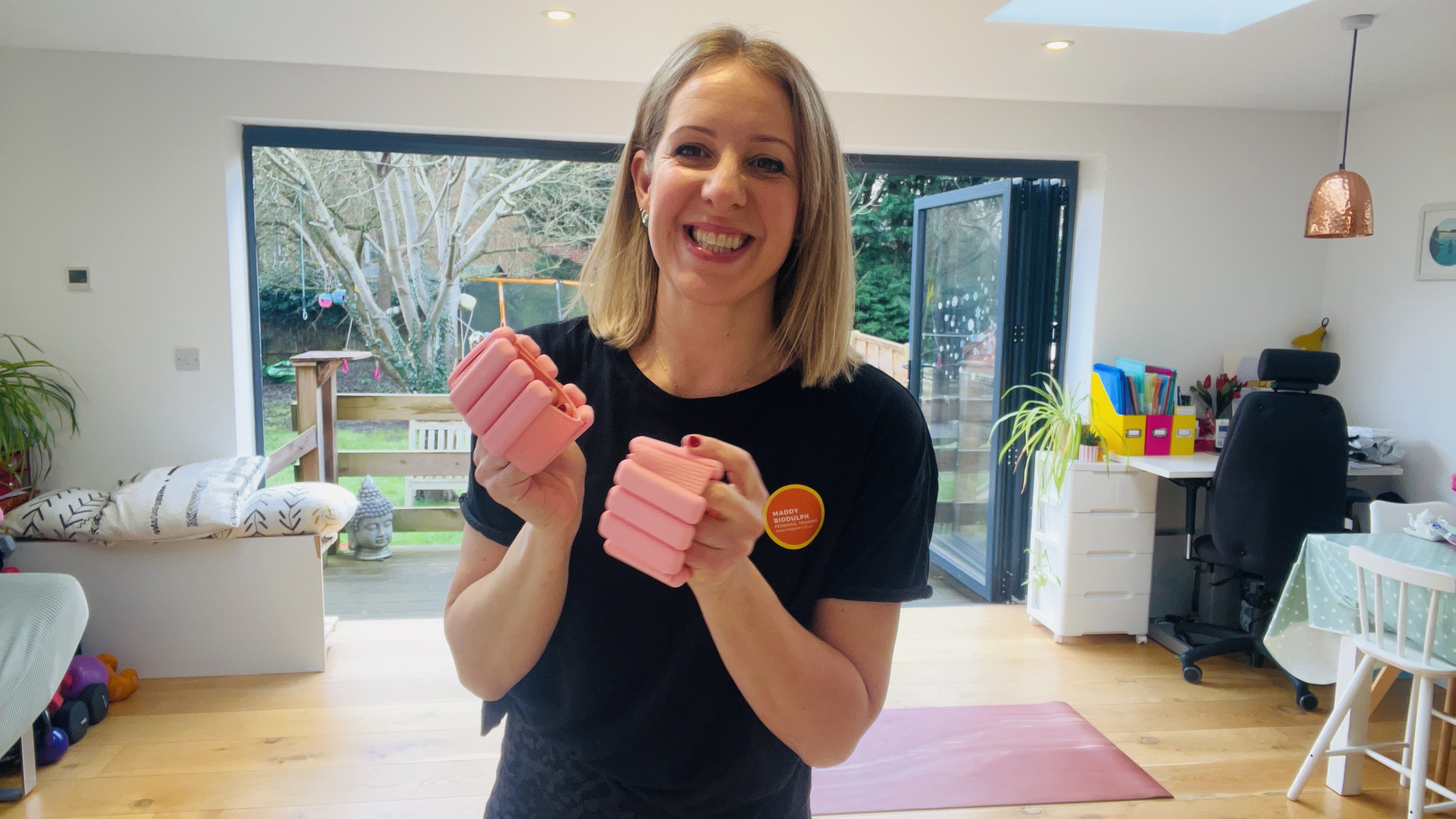Woman holds pink wrist weights in her hands