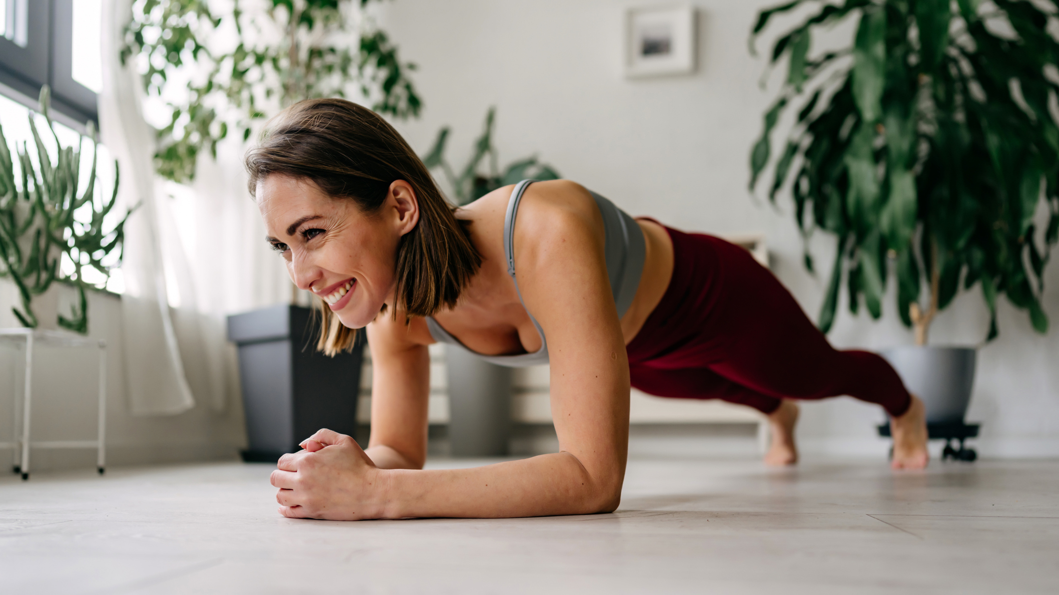 Smiling woman performing the plank exercise in a domestic setting