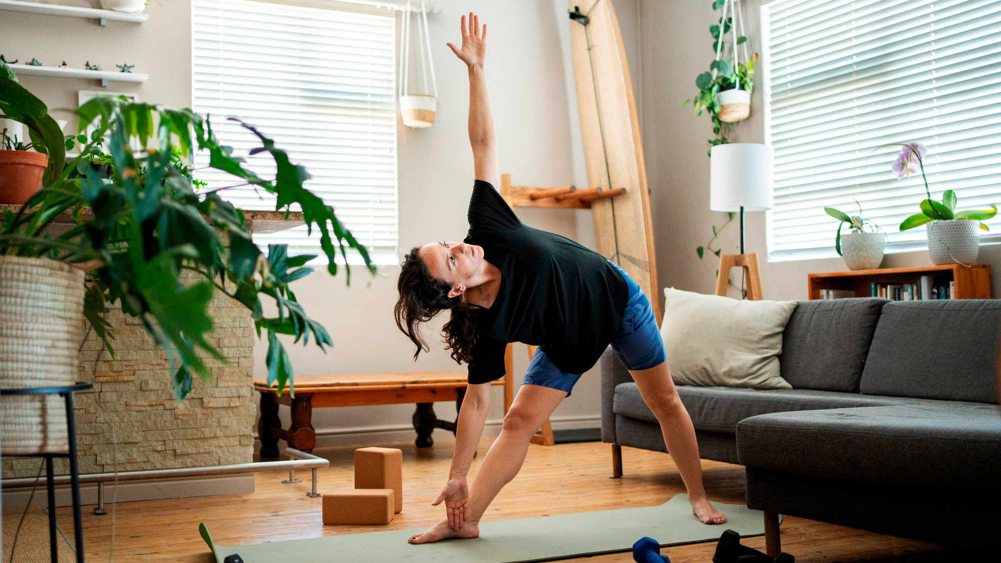 Woman performing Trikonasana yoga pose in a domestic setting