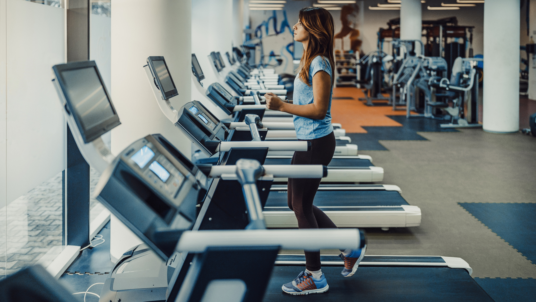 Woman walking on treadmill in empty gym