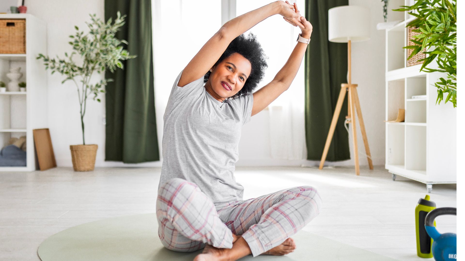 woman in pajamas sits on floor stretching arms overhead
